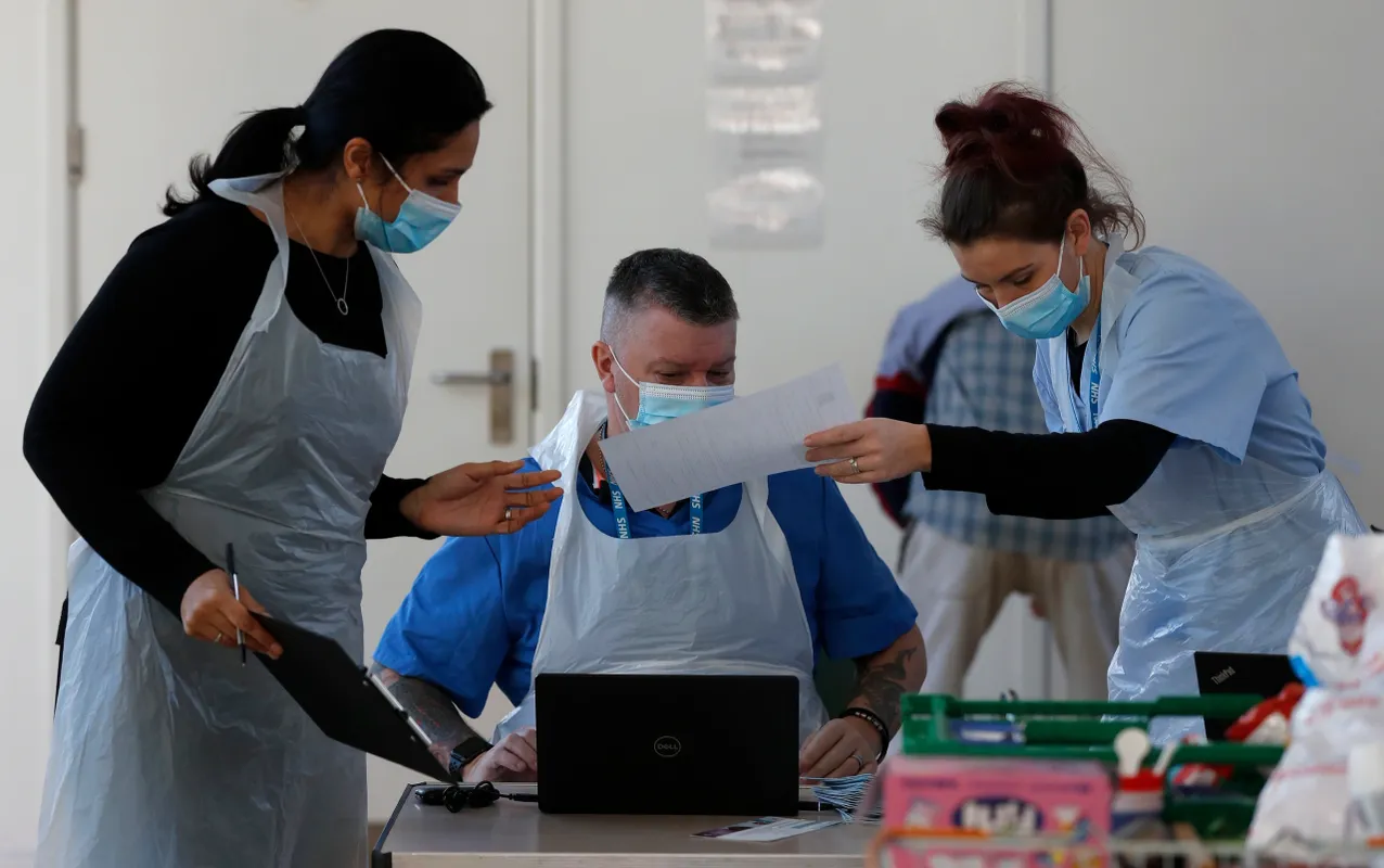 3 clinicians in PPE organising the vaccinations