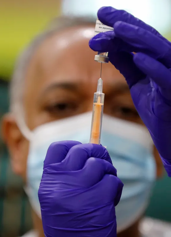 Clincian measuring a vaccine dose